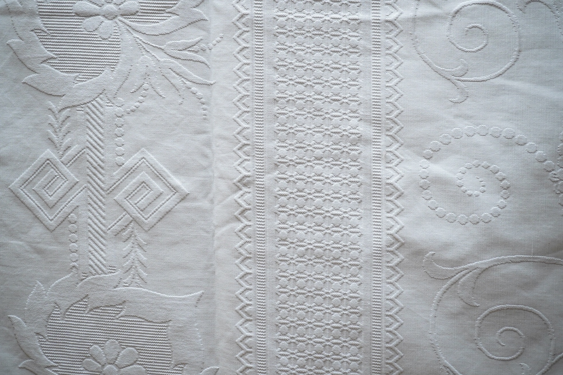 Three inspired Christopher Dresser white linen embossed bedcovers, with wide borders and ornate central designs, 216cm x 208cm. Condition - all good but will need rewashing.